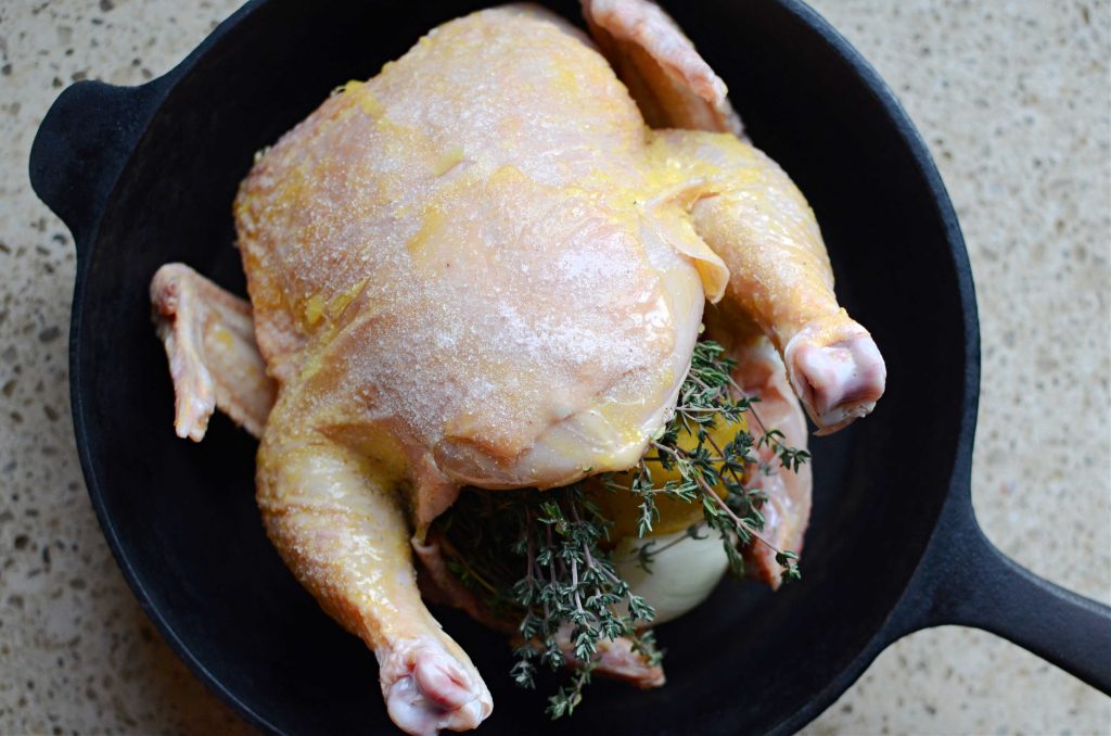 Whole chicken prepped to bake in cast iron skillet.