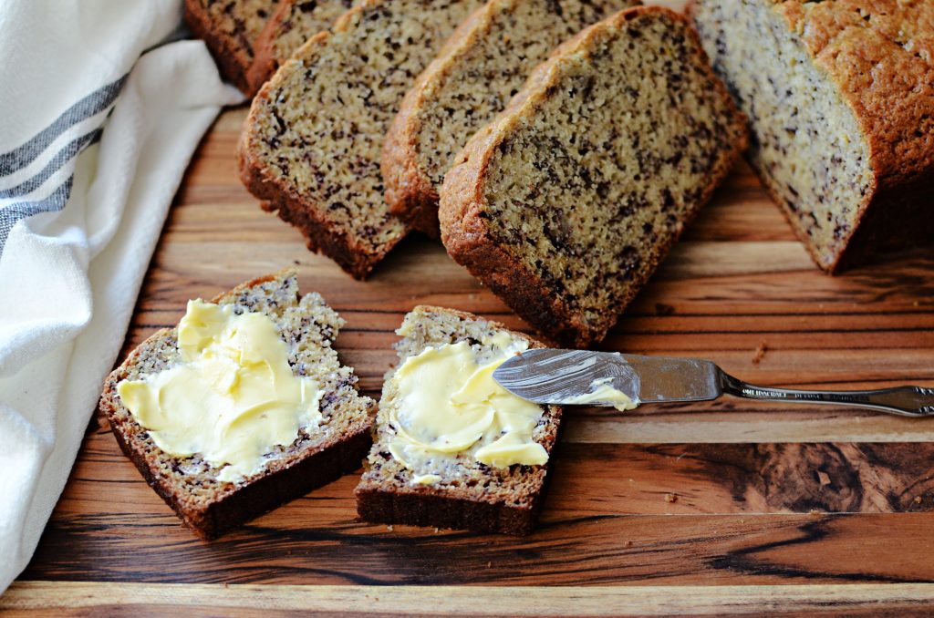 sliced banana bread with butter on wooden cutting board