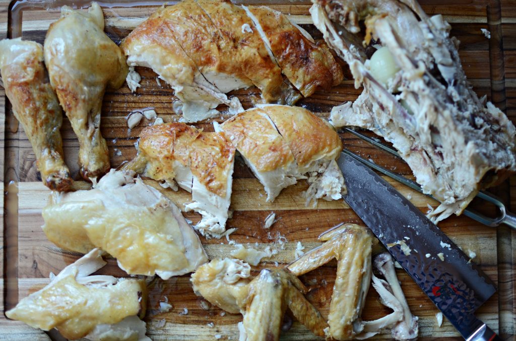 whole roasted chicken, cut up on wooden cutting board