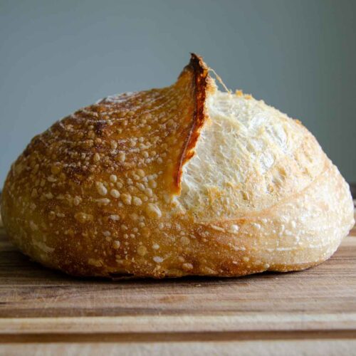 a loaf of sourdough bread on a wood cutting board