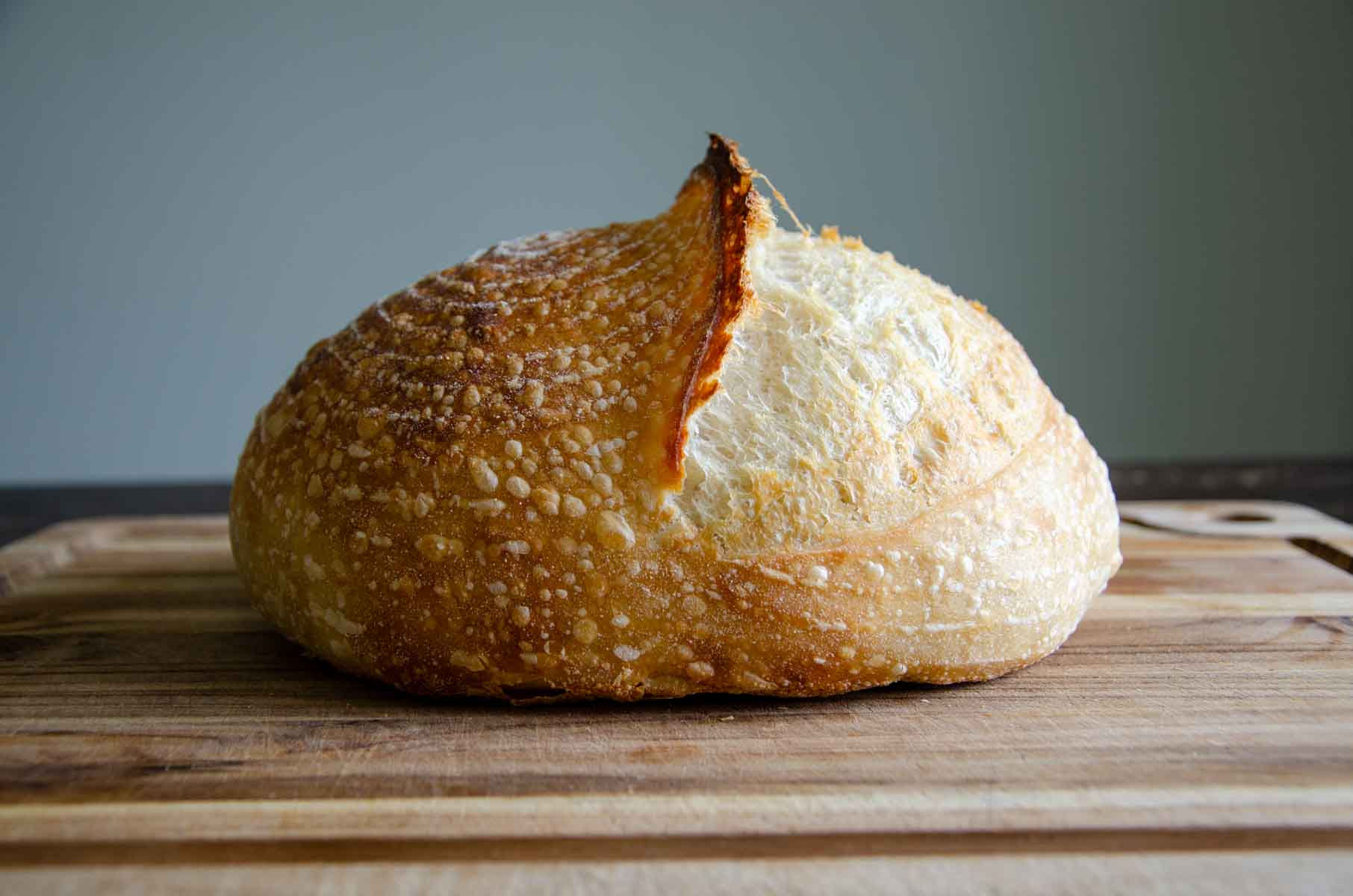 a loaf of sourdough bread on a wood cutting board