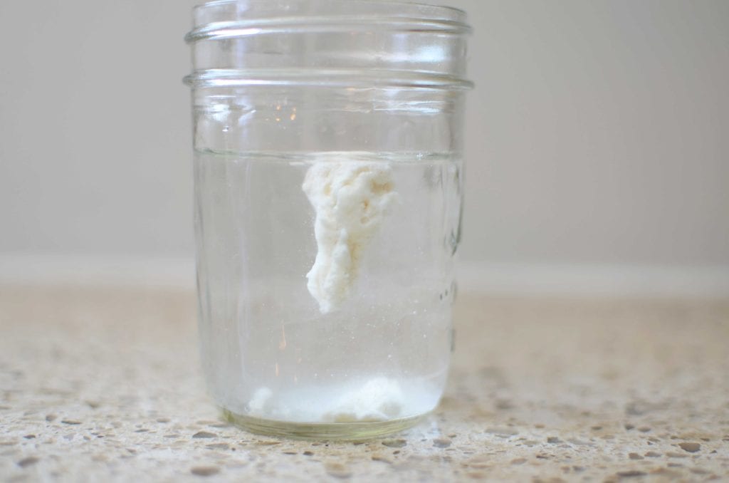 Sourdough starter floating in water in mason jar