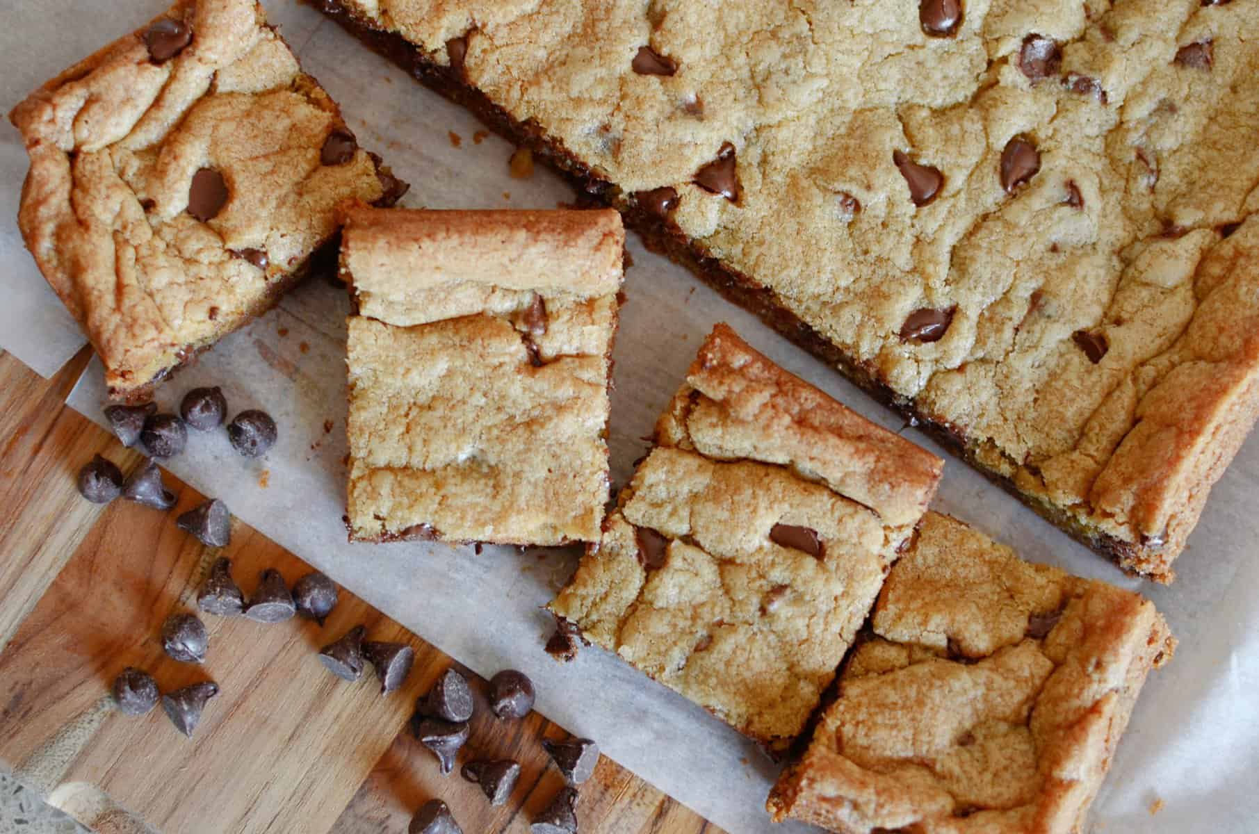 Cookie bars on parchment paper with chocolate chips sprinkled around