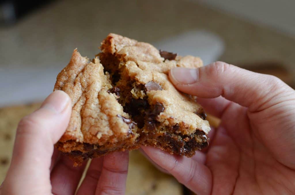 Womans hands breaking a chocolate chip cookie bar in half