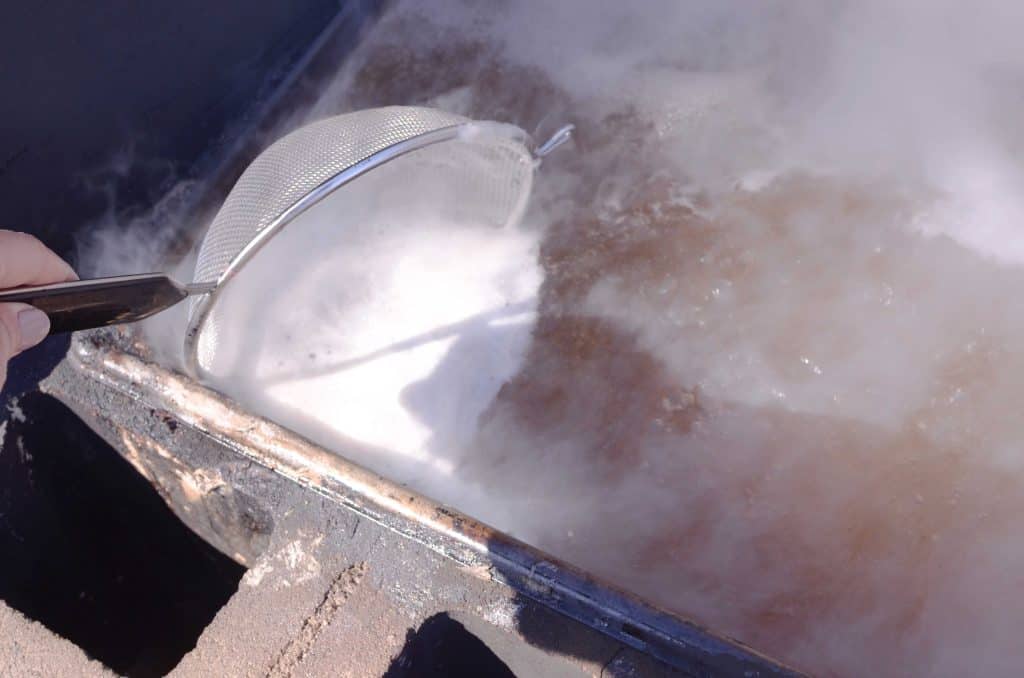 straining foam off of boiling sap with metal strainer