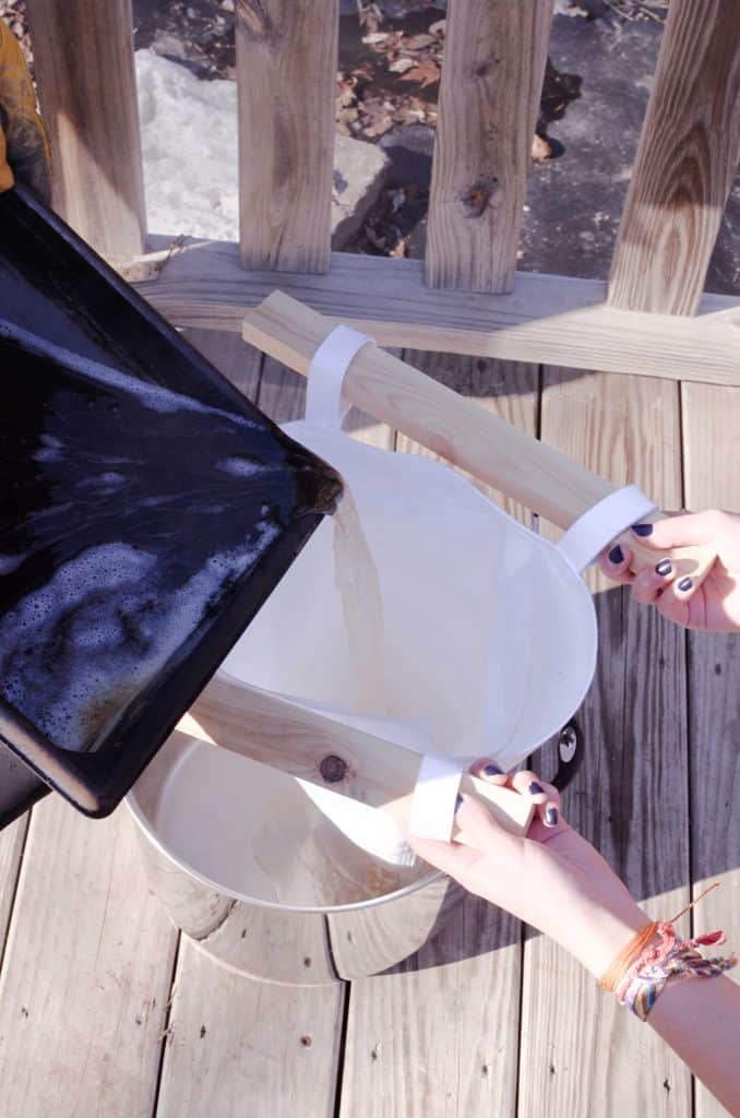 straining syrup into a cone filter outside