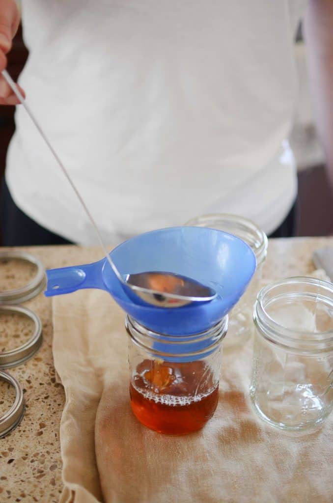 ladling syrup into pint size mason jar with funnel