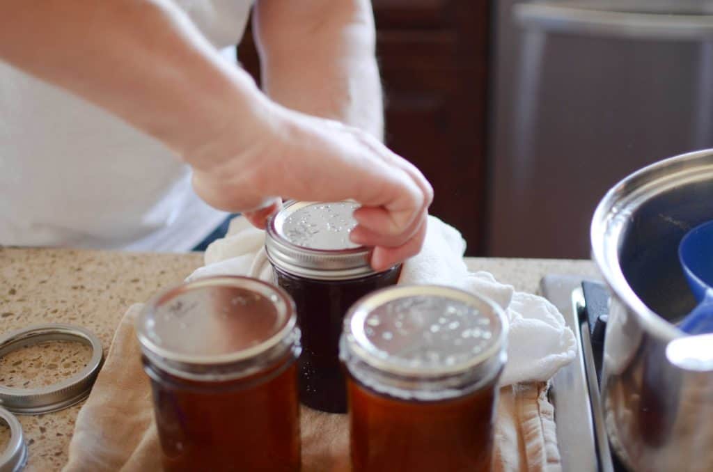 Tightening lid on mason jar filled with maple syrup