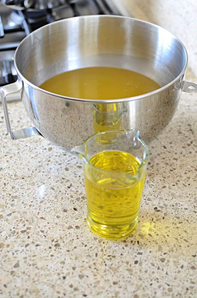 Melted tallow in metal bowl with olive oil in glass measuring cup