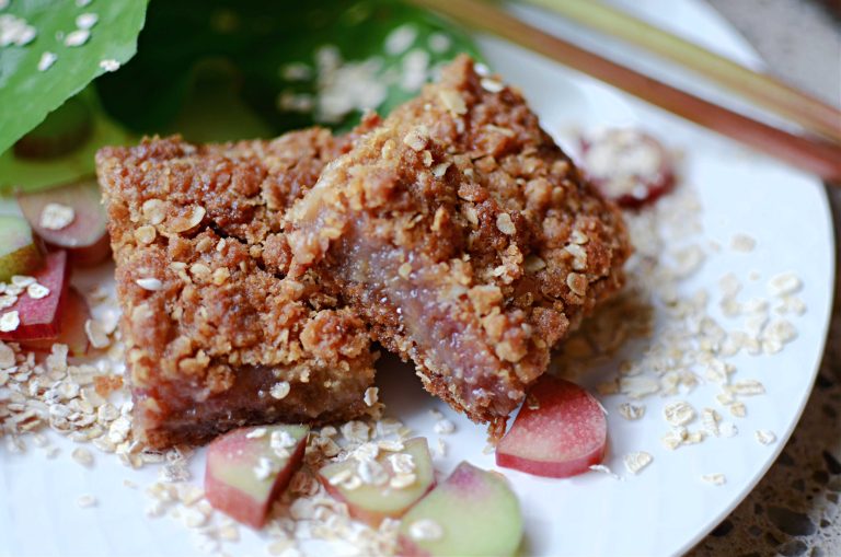 Two rhubarb bars on plate with rhubarb slices