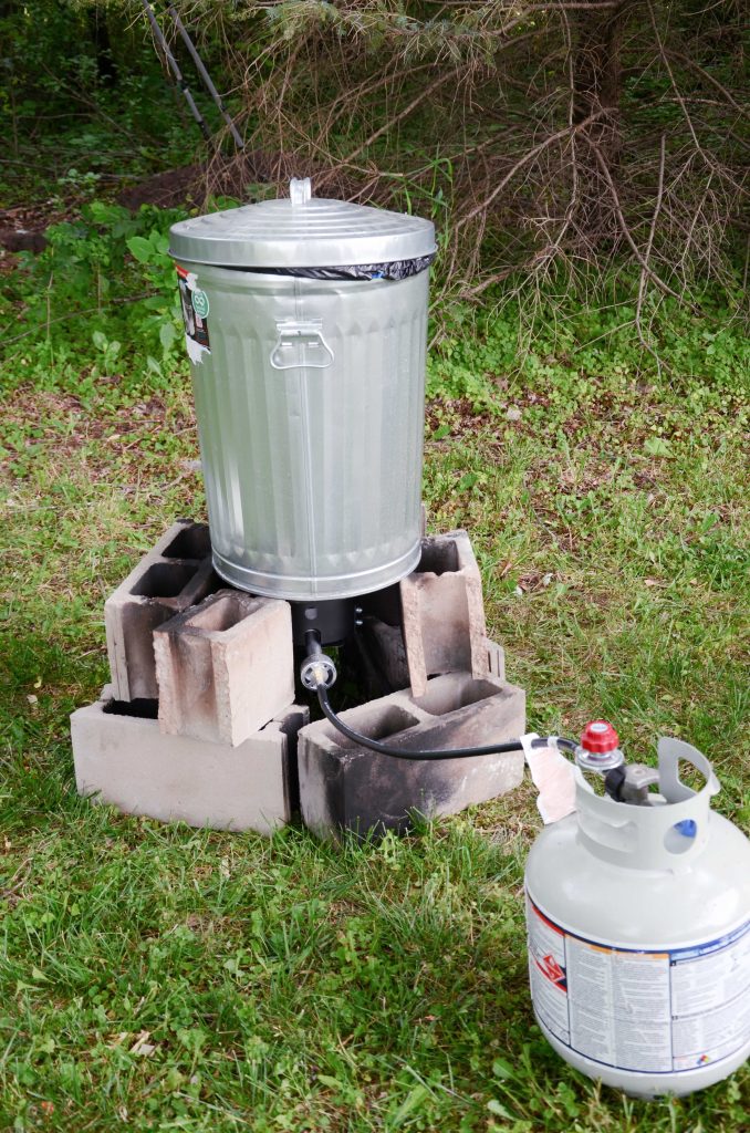 Metal garbage can on cinder blocks, over propane fish fryer  