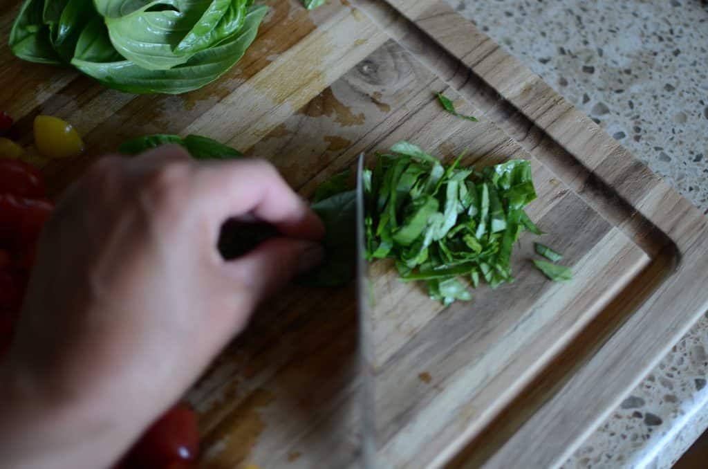 Slicing basil leaves on wood cutting board