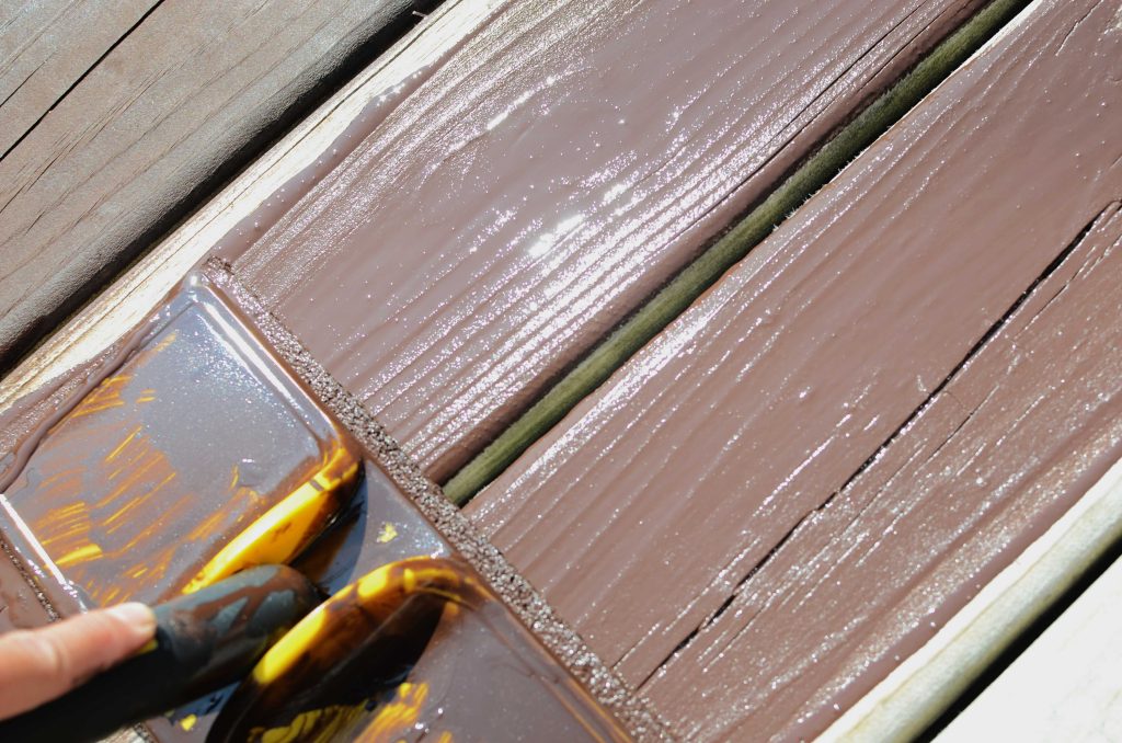 Applying stain with a pad on the deck boards,