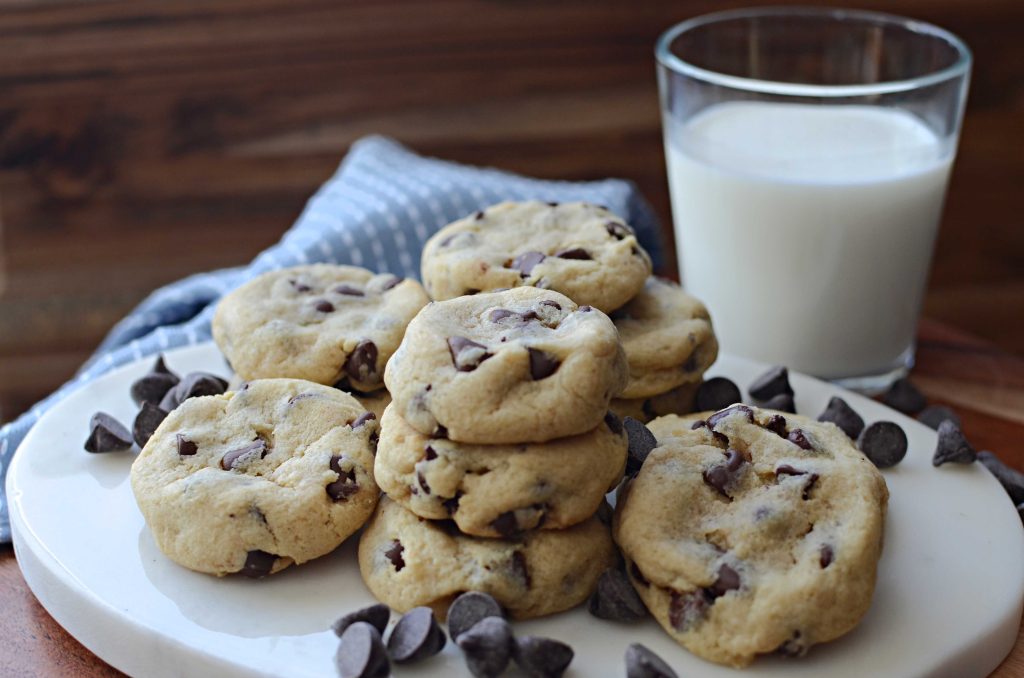 soft batch cookies stacked with a glass of milk behind