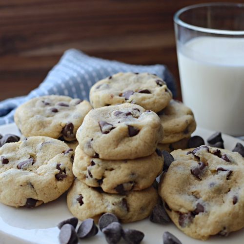 soft batch cookies stacked with a glass of milk behind