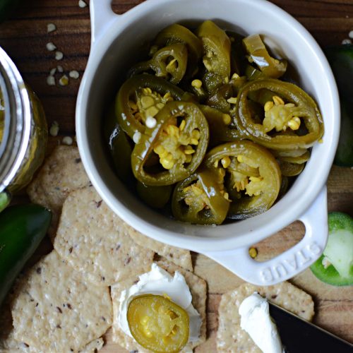 Dish of candied jalapenos with crackers. Cracker with cream cheese and sliced candied jalapeno.