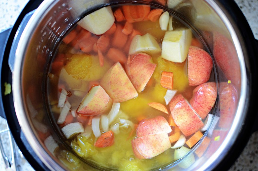 Instant pot filled with apple, onion, carrots, and cooked acorn squash