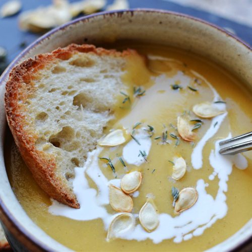 creamy acorn squash soup with roasted seeds and a piece of toast.