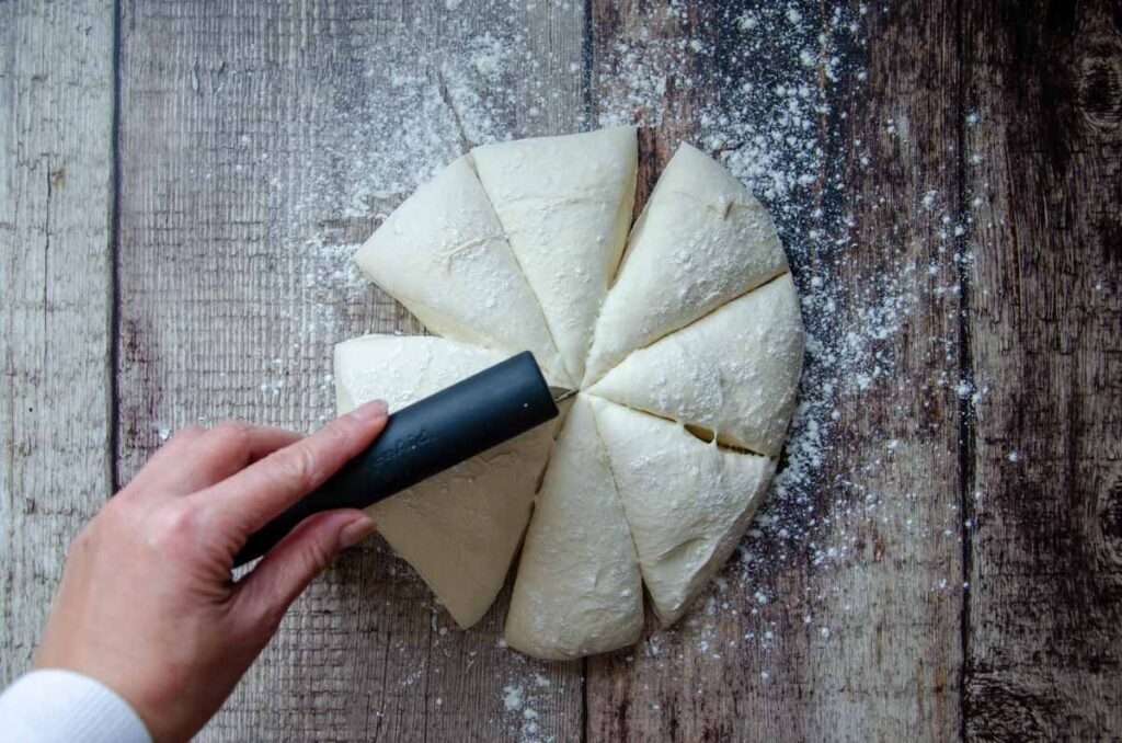 cutting the dough into 8 wedges using a bench scraper 