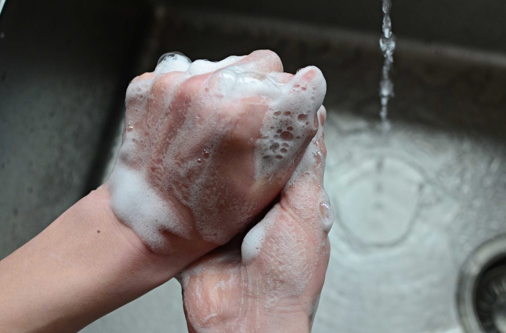 a pair of hands using foaming hand soap to wash hands