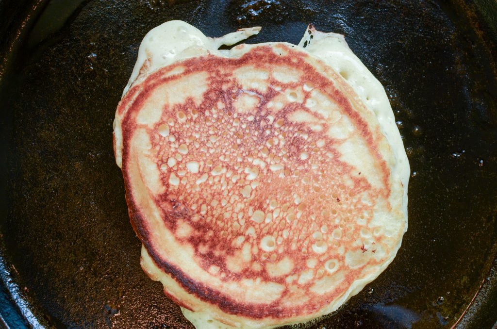 a flipped over sourdough pancake on cast iron skillet