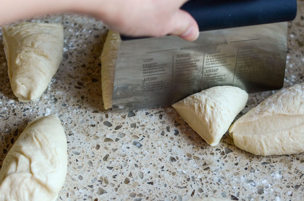 using bench scraper to divide sourdough tortilla dough into dough balls