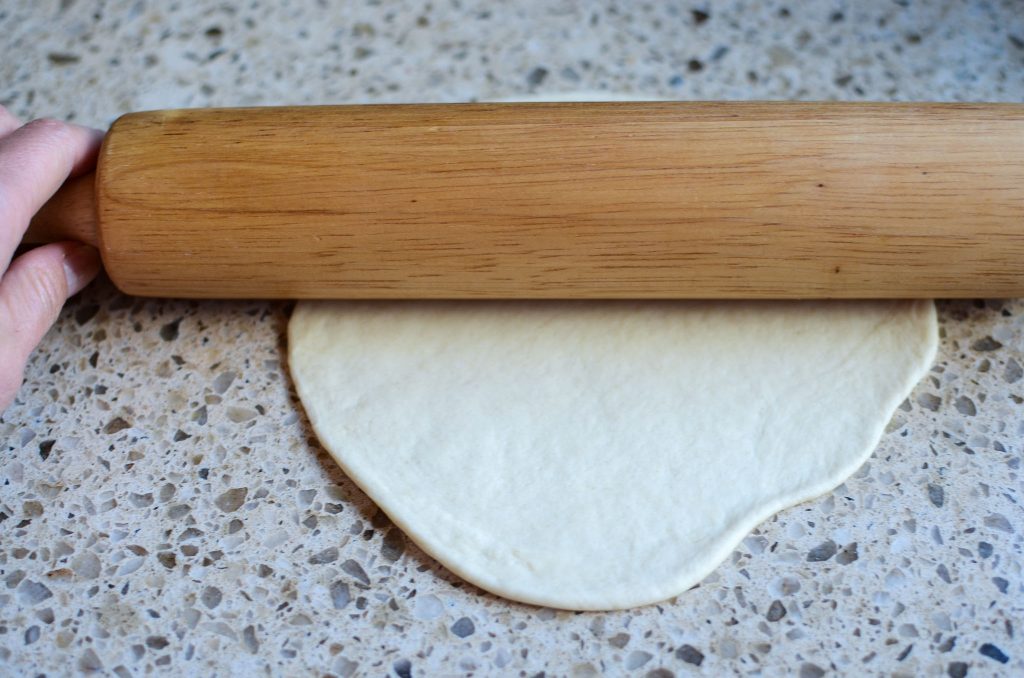 Rolling out sourdough flour tortilla with a wood rolling pin