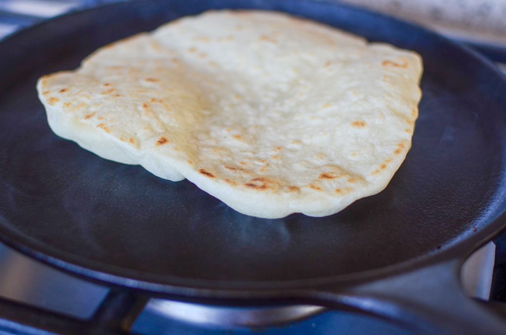 Flipped sourdough tortilla on a cast iron skillet