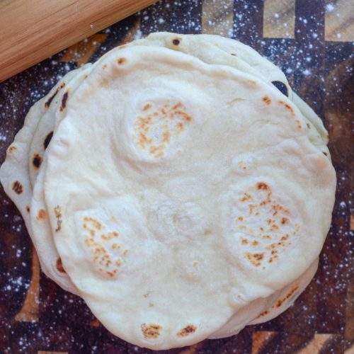 Sourdough flour tortilla stacked on wooden cutting board