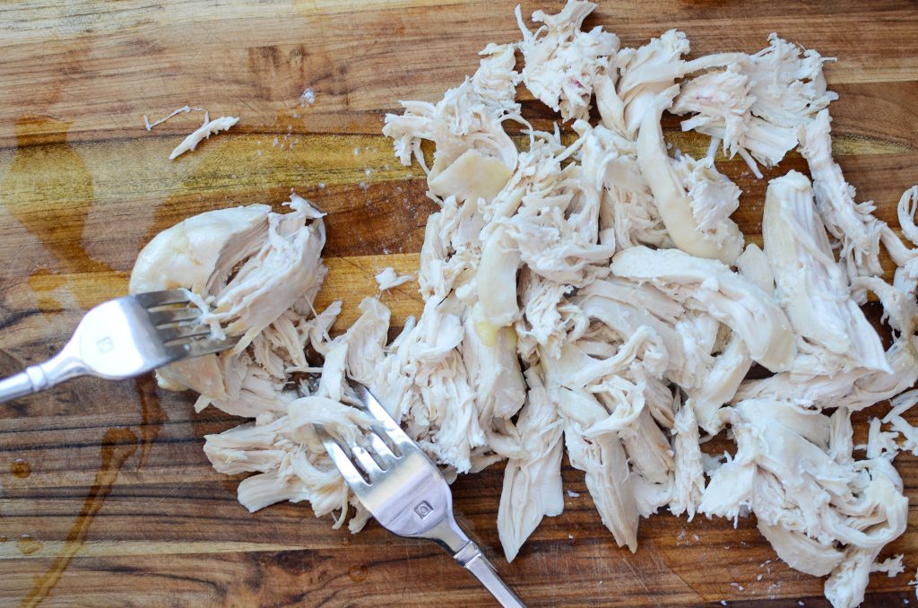 Shredded chicken on cutting board and forks