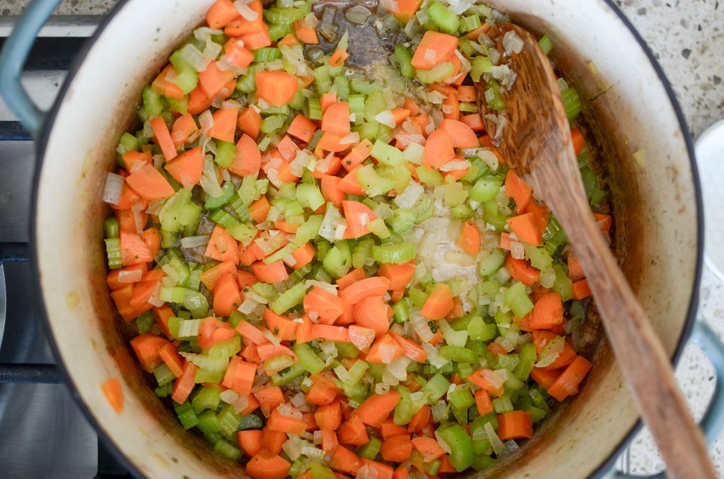 onion, celery, carrots and minced garlic in Dutch oven with wooden spoon.