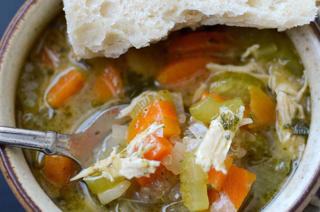 Chicken quinoa soup with spoon and piece of bread