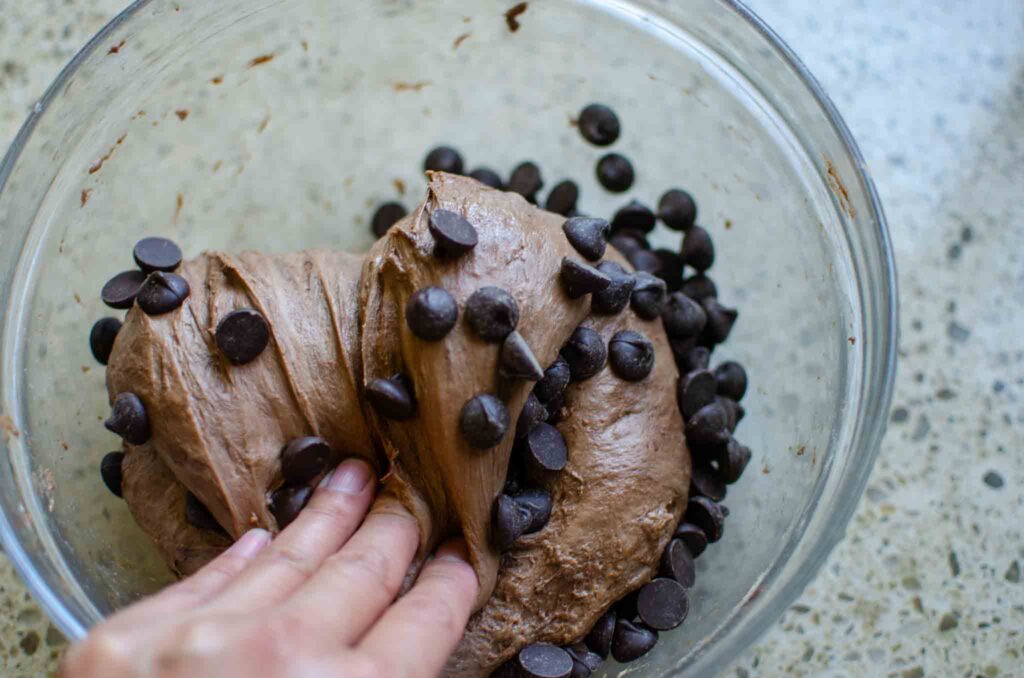 folding chocolate chips into chocolate sourdough bread dough