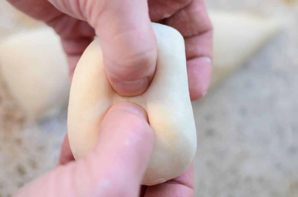 two hands poking a hole in the sourdough bagel dough ball