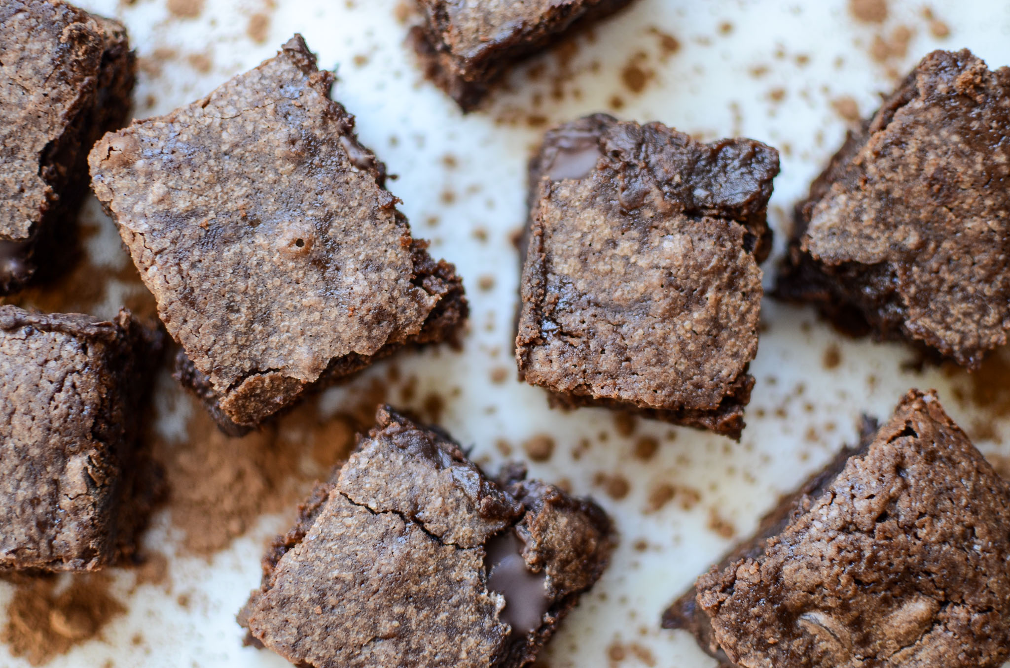 One-Bowl Fudgy Sourdough Brownies on marble with dusted cocoa powder