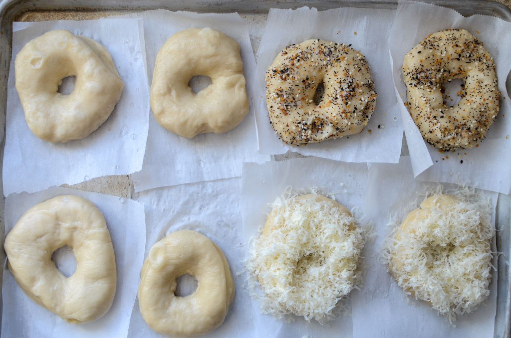 boiled sourdough bagels with toppings on parchment lined baking sheet