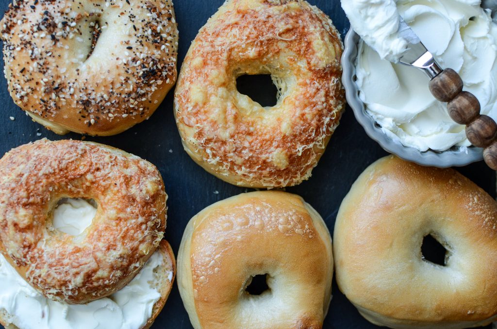 Sourdough bagels arranged on black stone with cream cheese