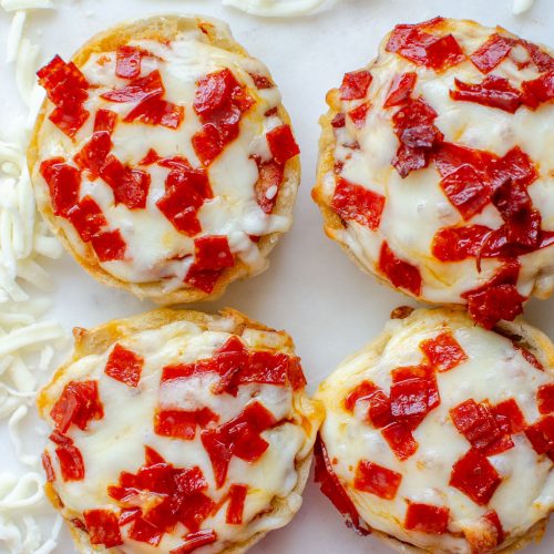 Four mini bagel bites with shredded mozzarella cheese and pepperoni slices next to bagel bites