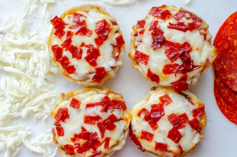 Four mini bagel bites with shredded mozzarella cheese and pepperoni slices next to bagel bites