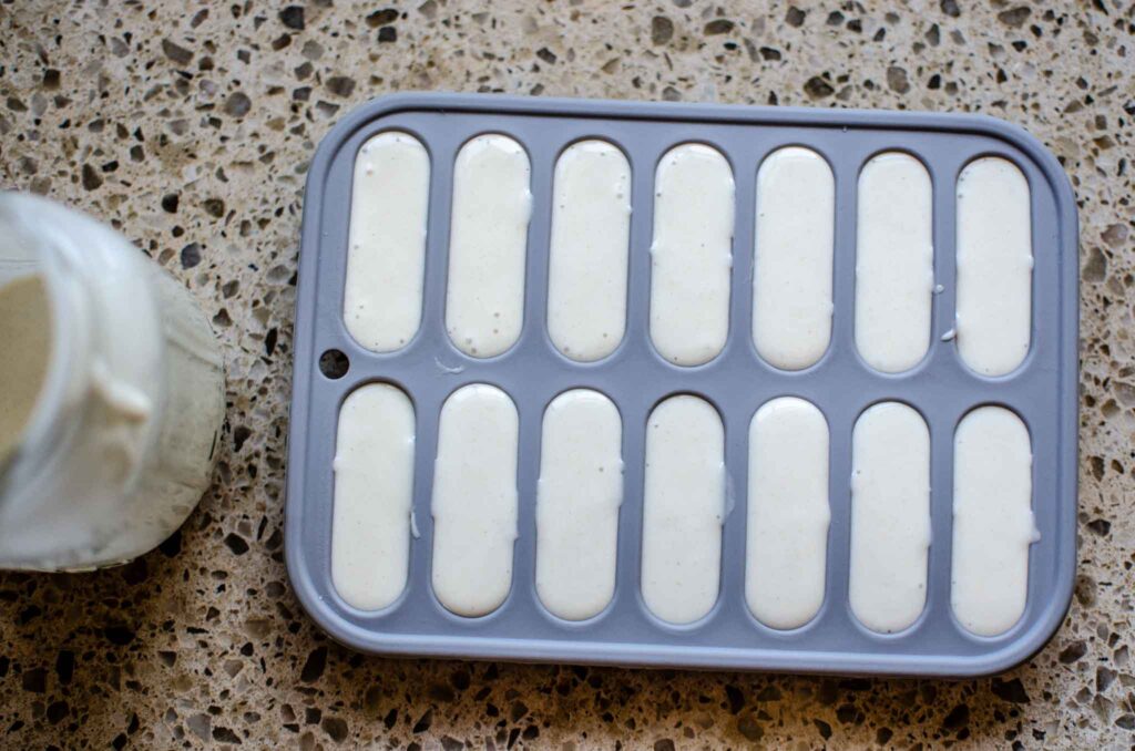 Sourdough discard in silicone molds with jar of sourdough starter 