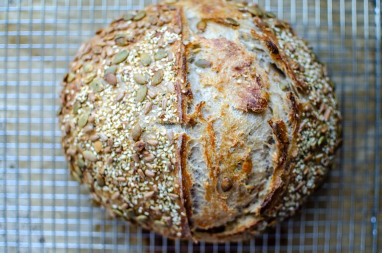 seeded multigrain sourdough bread loaf on wire rack