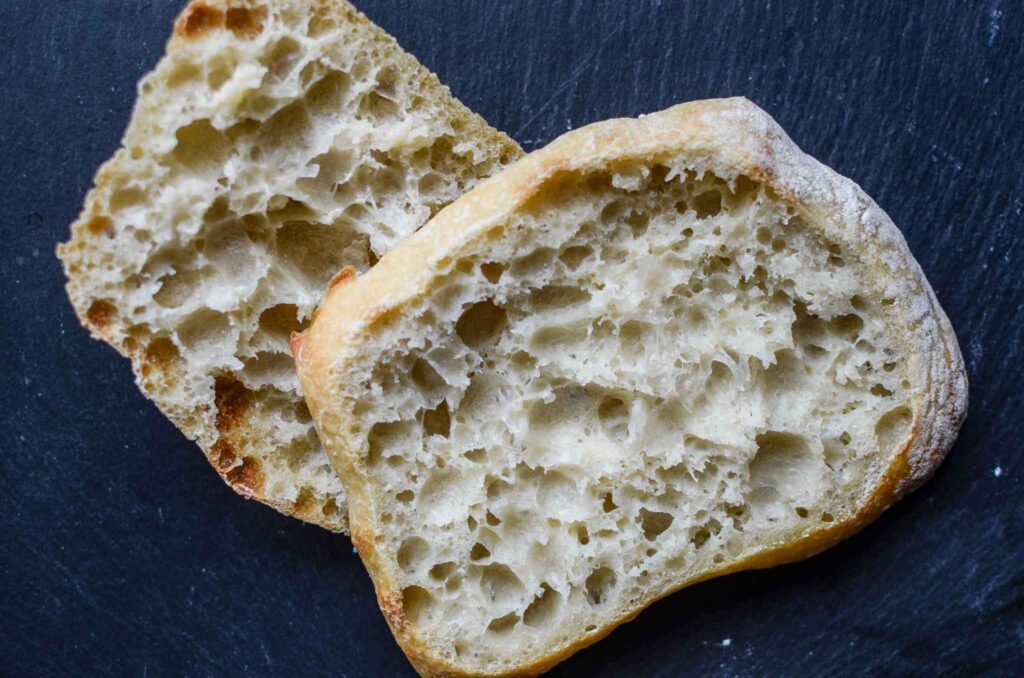 Sourdough ciabatta roll cut in half on black stone