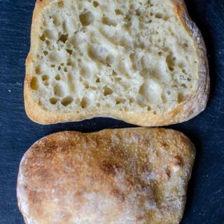 Sourdough ciabatta roll cut open on a black stone