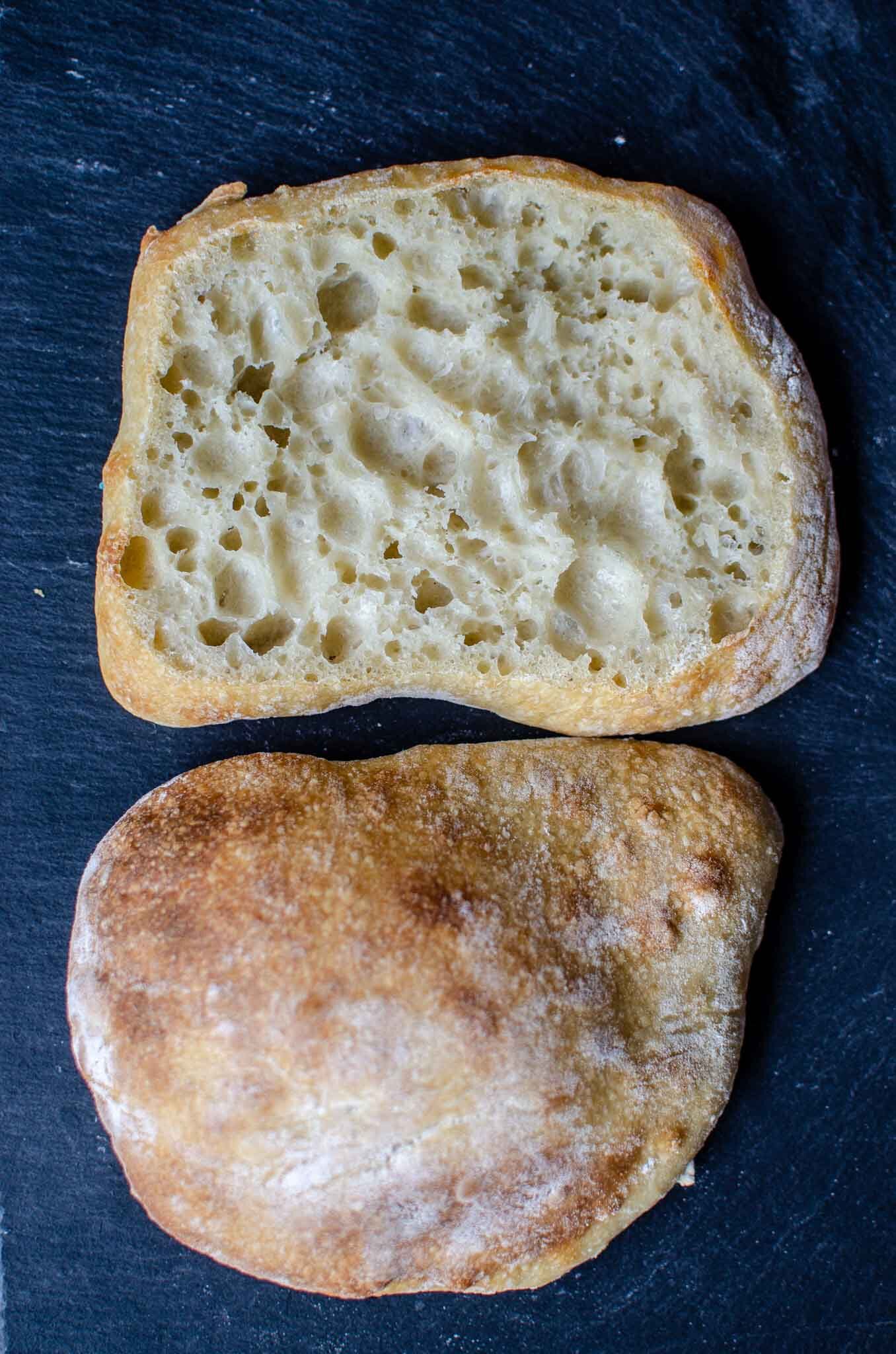 Sourdough ciabatta roll cut open on a black stone