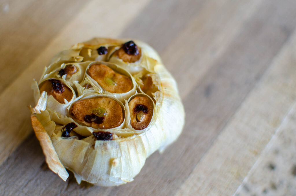 a bulb of roasted garlic on wood board