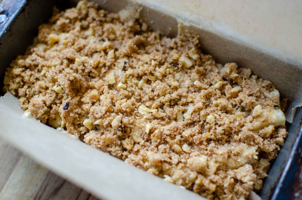 discard apple walnut bread loaf with streusel topping in parchment paper lined oaf pan