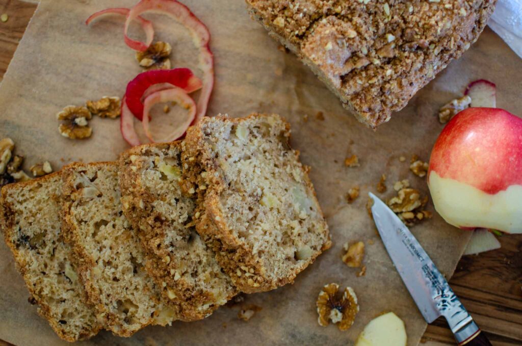 Discard apple walnut bread load sliced on parchment paper with apple peel and walnuts around