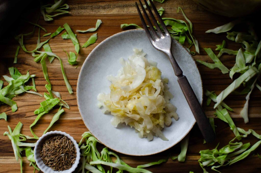 Probiotic Rich Homemade Fermented Sauerkraut  on plate with fork on wood cutting board