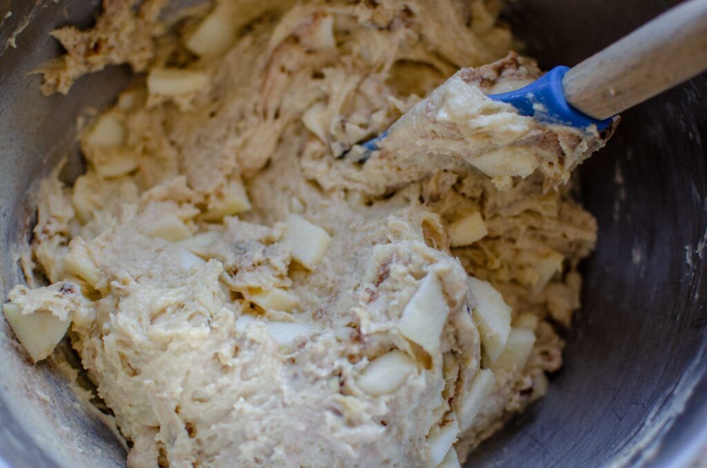 Folding apple chunks and chopped walnuts into discard apple walnut bread load batter