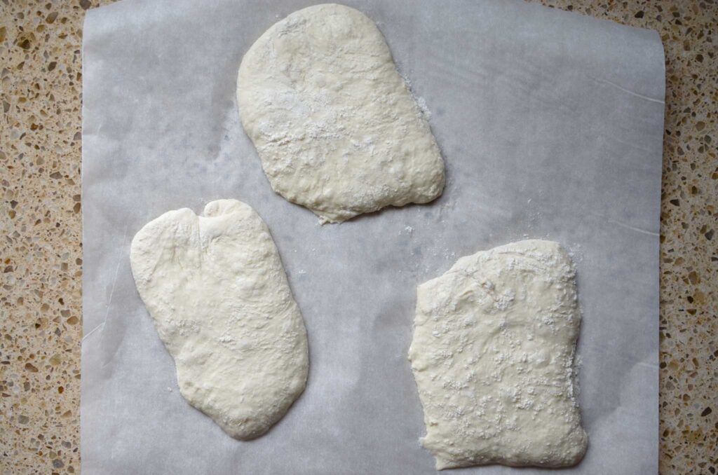 Sourdough ciabatta rolls on parchment paper during the final proof